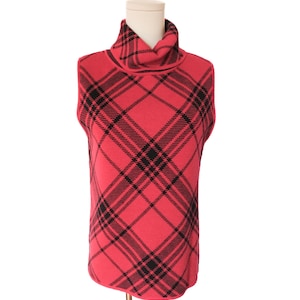 May include: A sleeveless, red turtleneck sweater with a black plaid pattern. The sweater is displayed on a mannequin and has a classic, preppy style. The fabric appears to be a knit material.