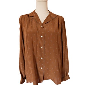 May include: A brown long-sleeve button-down shirt with a small paisley pattern. The shirt has a classic collar and white buttons. The shirt is displayed on a mannequin.