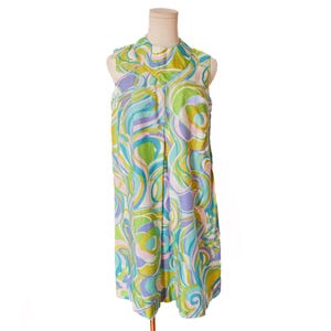 May include: A sleeveless, knee-length dress with a vibrant, swirling pattern in shades of green, blue, purple, and pink. The dress has a high collar and is displayed on a mannequin. The fabric appears to be lightweight.
