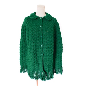 May include: A vibrant green, button-down knitted cardigan with a textured pattern and a fringed hem. The cardigan features a rounded collar and matching green buttons. The garment is displayed on a mannequin.