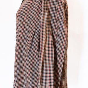 May include: A button-down shirt with a classic plaid pattern in shades of brown, black, red, and blue. The long-sleeved shirt is displayed on a mannequin, showcasing the collar, buttoned cuffs, and a chest pocket.
