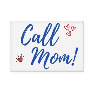 Puede incluir: Un imán rectangular blanco con las palabras "Call Mom!" en azul. Tres pequeños corazones rojos están encima de la palabra "Mom!" y un corazón rojo con líneas radiantes está a la izquierda de la palabra "Call".