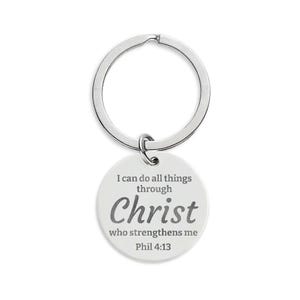 May include: A silver-colored keychain with a round, white pendant. The pendant features the text "I can do all things through Christ who strengthens me Phil 4:13" in a gray, stylized font. The keychain ring is circular.
