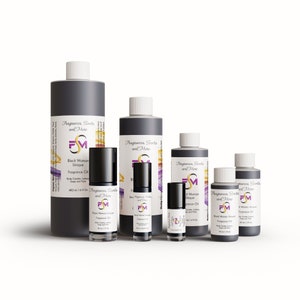 May include: Five different sized bottles of black fragrance oil with a white label. The label has the text "Fragrances, Scents and More" and a logo with the letters "FM". The text "Black Woman Unique Fragrance Oil" is also on the label.