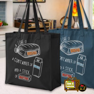 May include: Two tote bags, one black and one navy blue, each featuring a white graphic of a loaf of bread, a milk carton, and a stick of butter. Text on the bags reads "A loaf of bread, a container of milk, and a stick of butter."