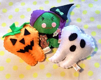 May include: Three handmade Halloween-themed felt ornaments: an orange jack-o'-lantern, a green witch with a black hat, and a white ghost. The witch has a cat pin and a wand. Each has a small tag that says "Tooth!".