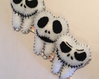 May include: Three white felt teeth with black facial features and stitched details, resembling a character. Each tooth has a small tag that reads "Tooth". The teeth are arranged diagonally on a light surface.