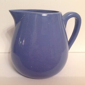 Könnte beinhalten: Eine hellblaue Keramikkanne mit rundem Körper und Henkel.