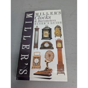 May include: A book titled "Miller's Clocks & Barometers Buyer's Guide" with a white cover and images of various clocks. The book's spine is dark with the word "MILLER'S" printed vertically. The cover features a variety of clock styles.