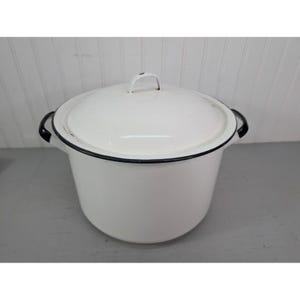 May include: A white enamel cooking pot with a lid. The pot has black trim around the rim and handles. The lid has a small handle. The pot is sitting on a gray surface.