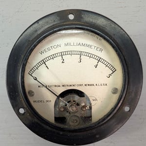 May include: A vintage Weston milliammeter with a black metal casing. The gauge has a white face with black markings, including the text "WESTON MILLIAMMETER" and numbers from 1 to 5. The needle points to just under 1. The text "WESTON ELECTRICAL INSTRUMENT CORP. NEWARK, N.J. U.S.A." is also visible.