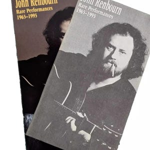 May include: Two black and white photo books with the title "John Renbourn Rare Performances 1965-1995" on the cover. The cover features a black and white photo of a man playing a guitar.