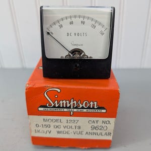 May include: A vintage Simpson DC Volts meter with a black frame and a white face. The meter reads up to 150 volts and is labeled "Simpson" and "DC VOLTS". It sits atop an orange box with the Simpson logo and product information.