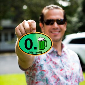May include: A person holding a green and yellow round sticker with the text "0. BEER RUN" and a green cartoon beer mug.