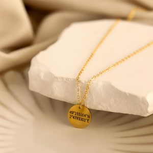 Puede incluir: Collar de oro con un colgante redondo que muestra las coordenadas 49°155164'N 2°4783301'E.