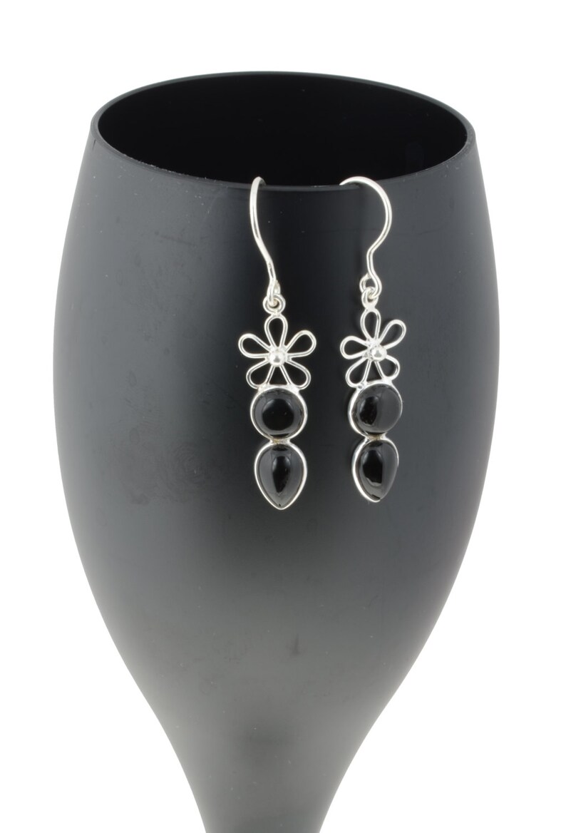 May include: Silver dangle earrings with black gemstone drops and flower accents.