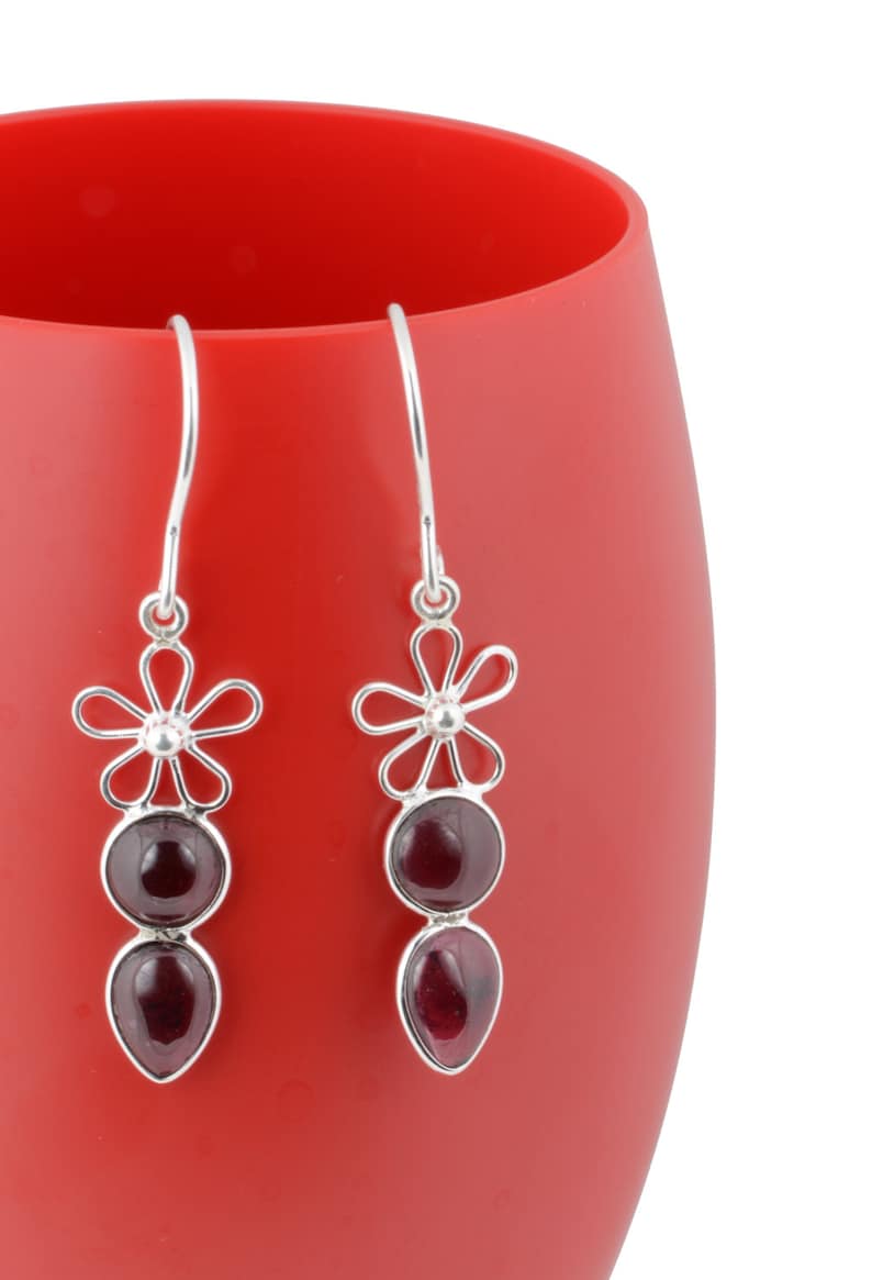 May include: A pair of silver dangle earrings with a flower design and two red gemstones.
