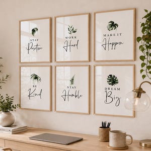Può includere: Un set di sei stampe artistiche da parete con cornici in legno chiaro, ognuna caratterizzata da un'illustrazione di foglia botanica e testo motivazionale tra cui Stay Positive, Work Hard, Make It Happen, Be Kind, Stay Humble e Dream Big su sfondo bianco.