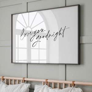 May include: A framed print with the words "love you, goodnight" in elegant black script. The artwork is displayed above a bed with white pillows and a wooden headboard. The wall is painted a soft green.