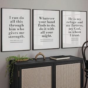 Puede incluir: Tres impresiones enmarcadas con marcos negros y fondos blancos, cada una mostrando una cita inspiradora diferente en texto negro. Las impresiones están encima de un mueble negro con puertas de mimbre.