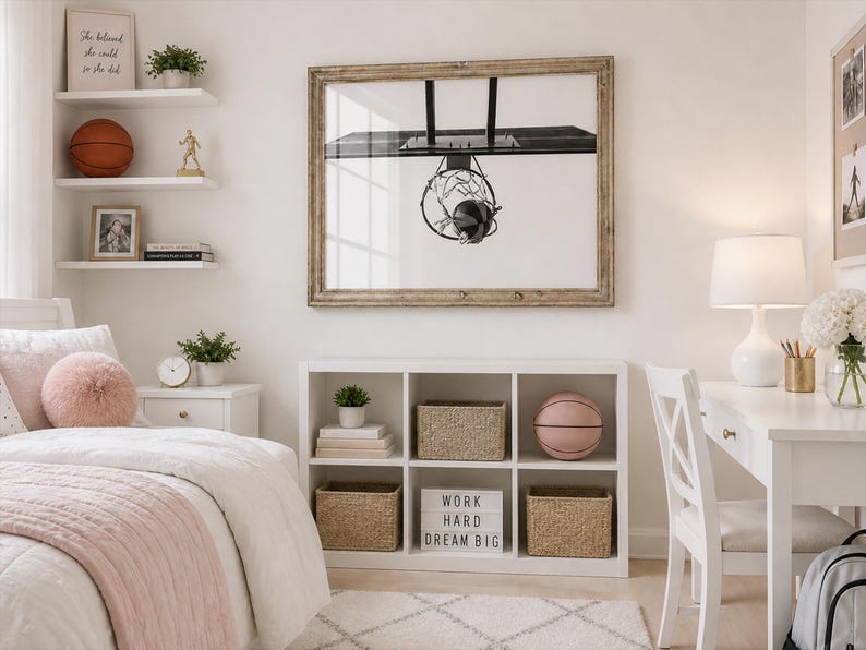 May include: A bedroom scene with a white desk, shelves, and bed. A framed basketball hoop art piece hangs above a white storage unit. A pink basketball and a sign that says "WORK HARD DREAM BIG" are visible.