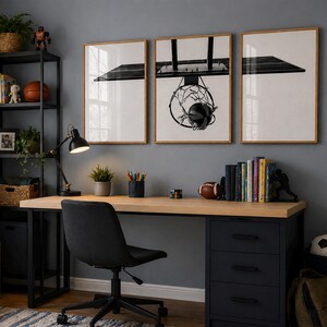May include: A home office setup featuring a light wood desk with a black three-drawer cabinet, a black office chair, and a black metal shelving unit. Three framed black and white prints of a basketball hoop hang on the gray wall above the desk.