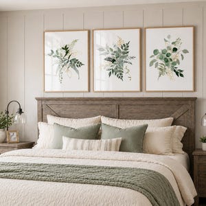 Puede incluir: Tres estampados bot&aacute;nicos enmarcados con follaje verde y dorado cuelgan sobre una cama con cabecero de madera. La cama est&aacute; hecha con ropa de cama color crema y acentuada con almohadas verdes y una colcha a juego. Dos mesitas de noche con l&aacute;mparas flanquean la cama.