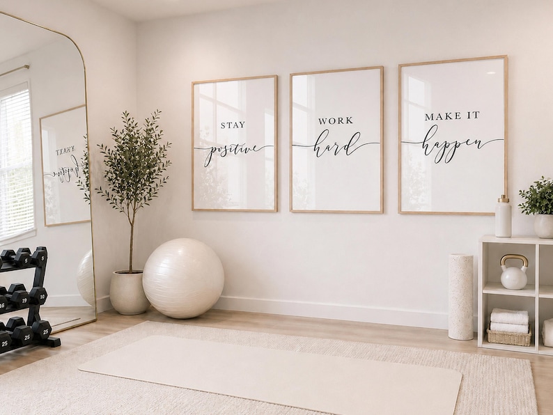 May include: A home gym interior with motivational wall art. Three framed prints with the phrases "Stay Positive", "Work Hard", and "Make It Happen" are displayed. A large mirror, exercise ball, and weights are also visible.