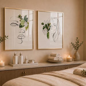 May include: Two framed art prints with gold frames, featuring line drawings of faces with floral accents. The scene includes spa-like decor: candles, rolled towels, and skincare products, creating a serene and relaxing atmosphere.