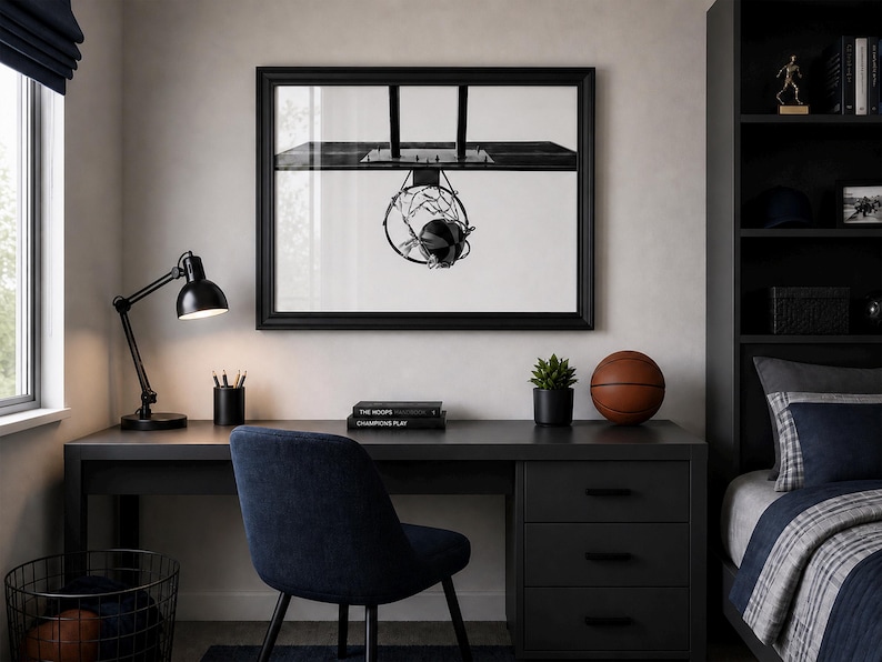 May include: A black desk with a black lamp, a basketball, and a framed black and white image of a basketball hoop. A blue chair sits in front of the desk. A small potted plant and a stack of books are also on the desk.