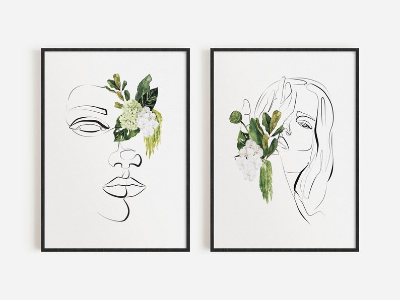 May include: Two framed art prints featuring minimalist line drawings of faces. One face has a closed eye and is partially adorned with green leaves and white flowers. The other print shows a face with long hair, also with floral accents. Both are in black frames.