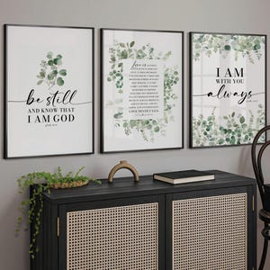 May include: Three framed prints with a white background and green watercolour floral designs. The prints feature the following text: "Be still and know that I am God", "Love is patient, love is kind", and "I am with you always".