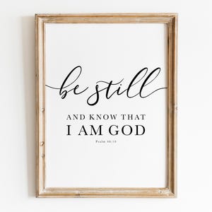 Può includere: Stampa incorniciata con le parole "be still and know that I am God" in nero. La cornice è di colore marrone chiaro. Il testo è tratto dal Salmo 46:10.