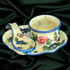 May include: A white ceramic serving dish with a blue rim and floral design. The dish features a small bowl with a blue rim and a matching spoon with a handle.