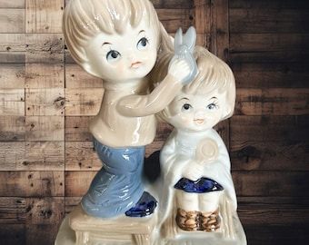 Unmarked glazed vintage 1980s porcelain figurine boy giving sister haircut