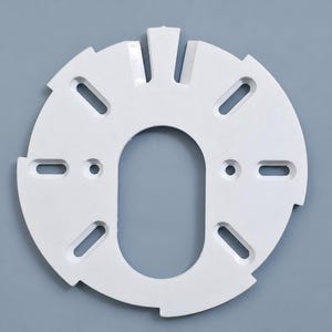 May include: A circular white mounting plate featuring a central elongated oval cutout, four smaller circular holes, and six evenly spaced rectangular slots along the perimeter, with a notched edge design for secure installation and alignment.
