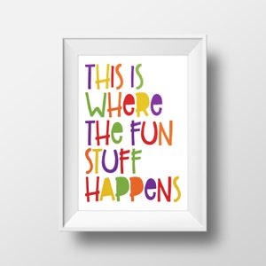 May include: A framed print with the text "THIS IS WHERE THE FUN STUFF HAPPENS" in colorful, playful lettering. The words are in various bright colors, including yellow, green, red, and purple, against a white background. The frame is white.