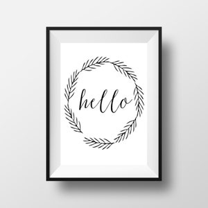 May include: A framed print featuring the word "hello" in elegant cursive script, encircled by a wreath of stylized leaves. The artwork is in black and white, with a minimalist design. The frame is black.