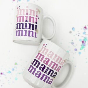 May include: Two white ceramic mugs with a gradient design. The top mug says "mini" four times in a pink, purple, and blue gradient. The bottom mug says "mama" four times in a pink, purple, and blue gradient.