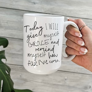 May include: White ceramic mug with black text that reads "Today I will give myself grace and remind myself how far I've come."