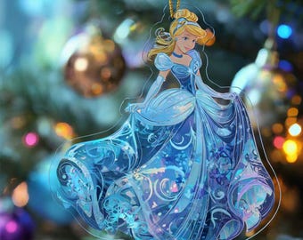 May include: A clear acrylic Christmas ornament depicting a princess in a blue gown. The princess has blonde hair and is wearing a blue choker. The ornament hangs from a gold string, with a blurred Christmas tree background.