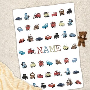 K&ouml;nnte beinhalten: Eine wei&szlig;e rechteckige Decke mit einem wiederkehrenden Muster aus verschiedenen bunten Cartoon-Autos aus dem Film Cars, darunter rote, blaue, gelbe und braune Fahrzeuge. Das Wort NAME ist in gro&szlig;en, mehrfarbigen Blockbuchstaben in der Mitte gedruckt.