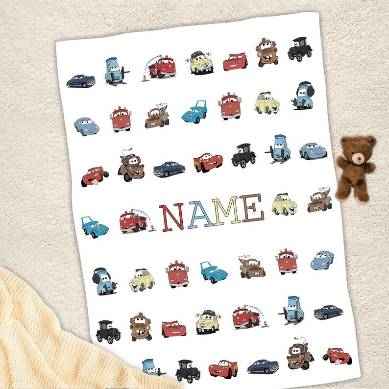 K&ouml;nnte beinhalten: Eine wei&szlig;e rechteckige Decke mit einem wiederkehrenden Muster aus verschiedenen bunten Cartoon-Autos aus dem Film Cars, darunter rote, blaue, gelbe und braune Fahrzeuge. Das Wort NAME ist in gro&szlig;en, mehrfarbigen Blockbuchstaben in der Mitte gedruckt.
