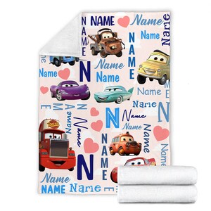May include: A soft fleece blanket featuring a repeating pattern of characters from the movie Cars, including Mater, Lightning McQueen, and others. The design includes the word Name in various blue fonts, pink hearts, and white clouds on a light background.