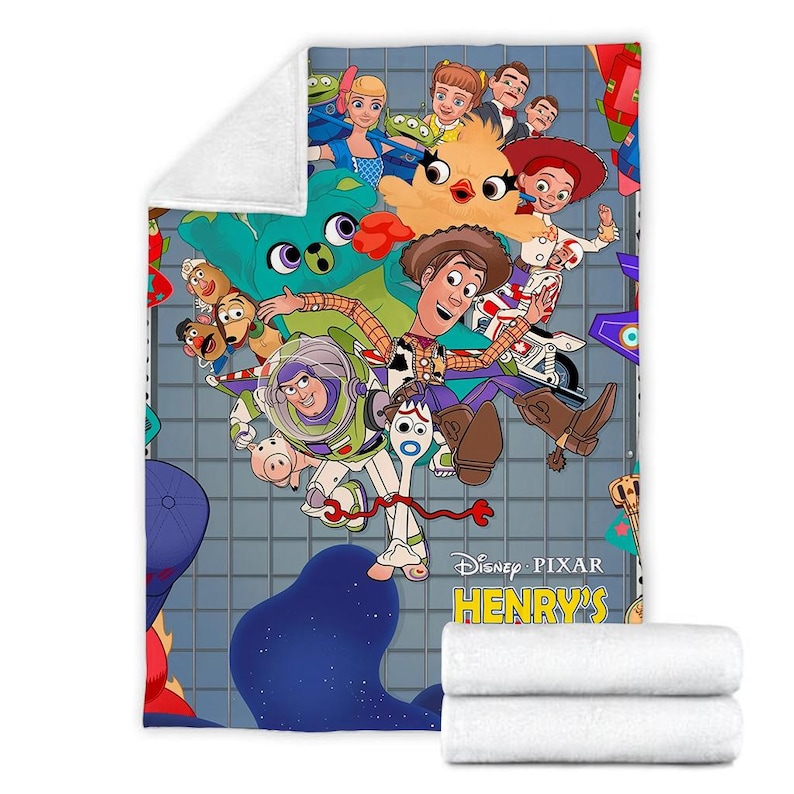 K&ouml;nnte beinhalten: Eine bunte Decke mit Figuren aus dem Disney Pixar Film Toy Story. Die Decke zeigt Woody, Buzz Lightyear, Jessie und andere Figuren aus dem Film. Die Decke ist blau, gr&uuml;n und gelb mit einem Sternenmuster. Der Text "Disney Pixar Henry's" ist auf der Decke aufgedruckt.