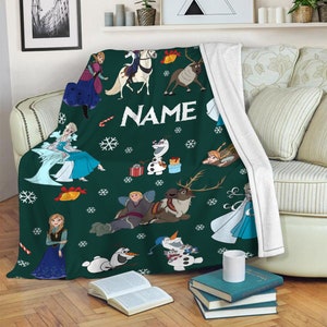 May include: A dark green fleece throw blanket featuring a repeating pattern of characters from Frozen, including Elsa, Anna, Olaf, Kristoff, and Sven. The design includes white snowflakes, candy canes, bells, and the word NAME in white text.