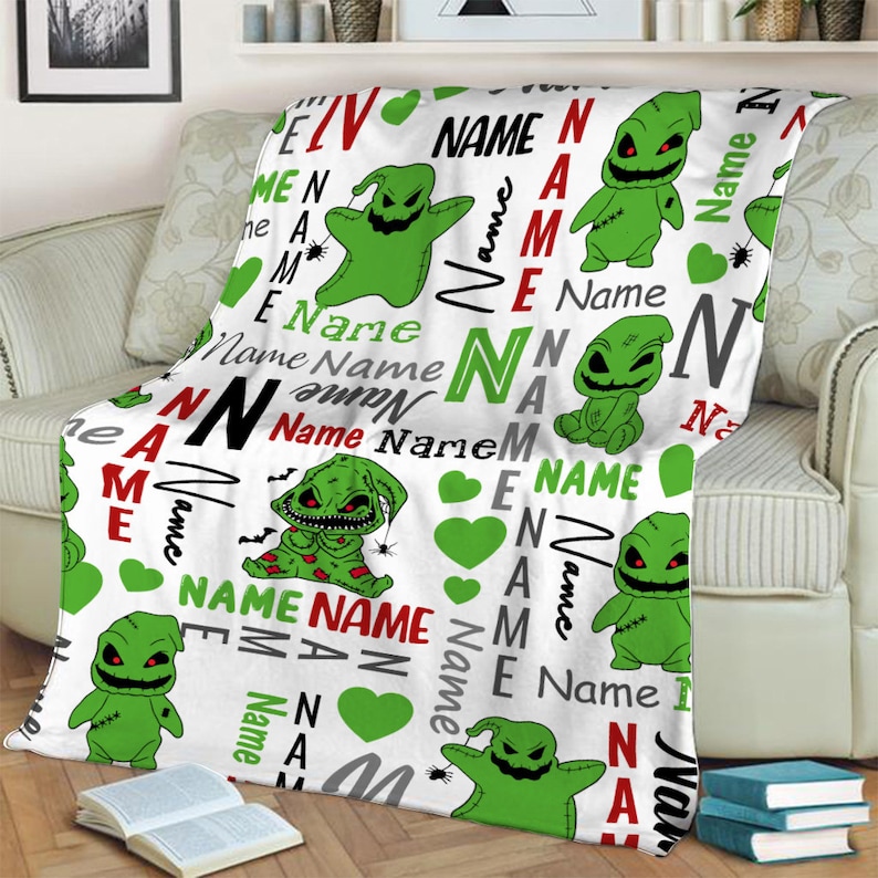 May include: White fleece blanket with a green and black repeating pattern of a cartoon character with stitches and a green heart. The text "Name" is repeated throughout the blanket in red, black, and gray.