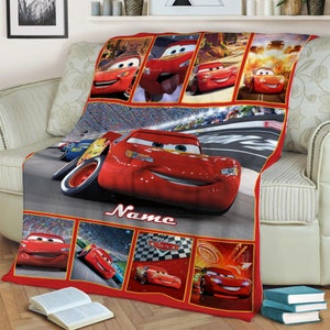 Puede incluir: Una manta rectangular de forro polar con m&uacute;ltiples escenas del personaje de coche de carreras rojo Lightning McQueen de la pel&iacute;cula Cars. El dise&ntilde;o incluye una gran imagen central del coche en una pista con la palabra Name en letra cursiva.