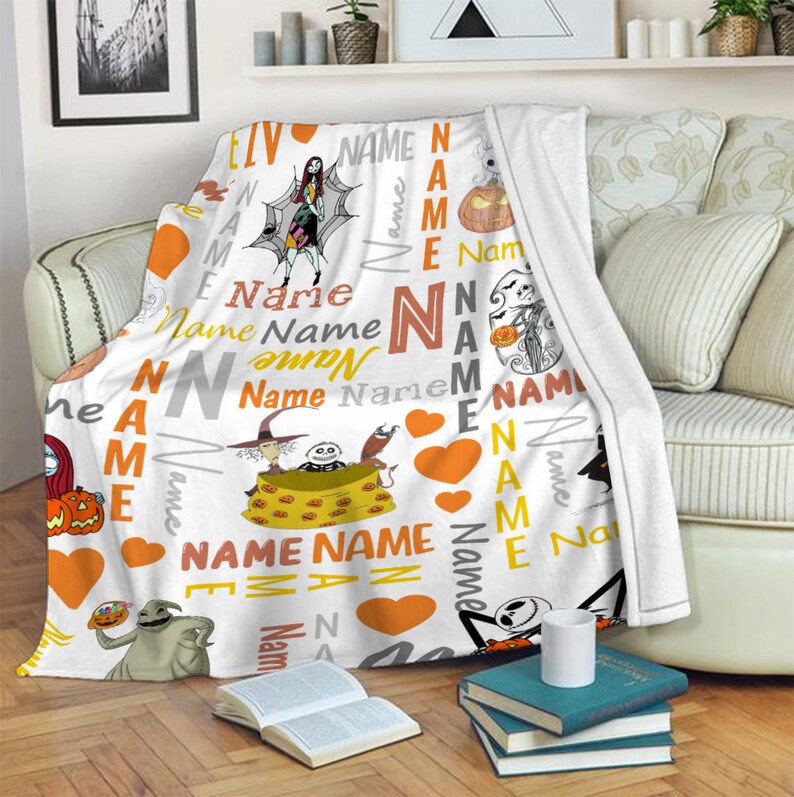 May include: A white fleece throw blanket featuring a repeating pattern of characters from The Nightmare Before Christmas, including Sally, Jack Skellington, and Oogie Boogie, interspersed with orange hearts and the word Name in various fonts.