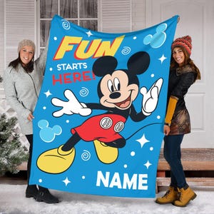 May include: Blue fleece blanket with a cartoon image of Mickey Mouse. The blanket has the text "Fun Starts Here!" and a space for a name.